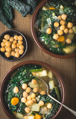 Black cabbage (Tuscan kale) soup or  minestra Toscana with chickpeas in clay traditional bowls, wooden background. Italian Tuscan winter recipes. Recipes of Medici family