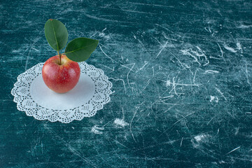 single delicious apple on the doily , on the blue background