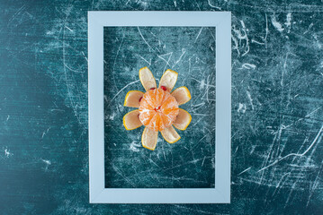 peeled tangerine in the frame on the blue background