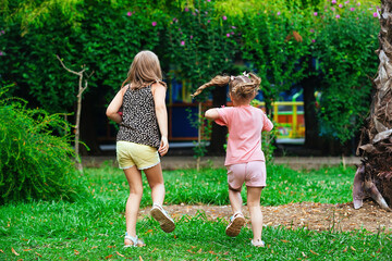 children, two little sister girls of different ages have fun running to the amusement park on a...