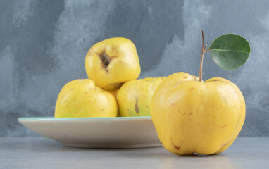 Quinces on and next to a platter on marble background