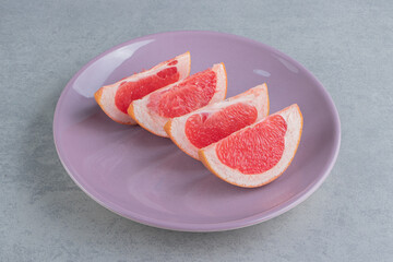 Grapefruit slices on a platter on marble background