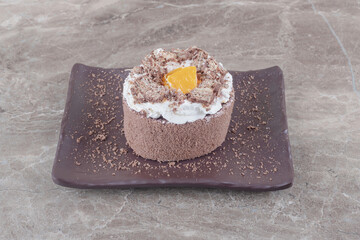 Small cake with chopped orange topping on a platter on marble background