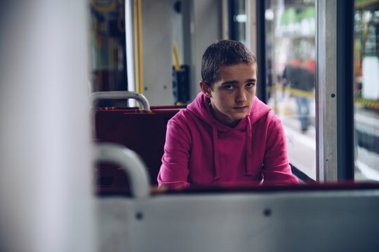 Teenage Boy In A Pink Hooded Sweatshirt, Pensive, Sad, Is Traveling By Bus