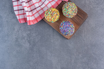 Fototapeta na wymiar Colorful pralines decorated with sprinkles on wooden board