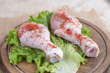 Uncooked chicken legs meat with vegetables on a wooden board