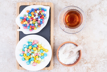 A cup of hot tea with colorful candies