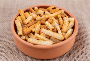A clay bowl of breadsticks on a sackcloth