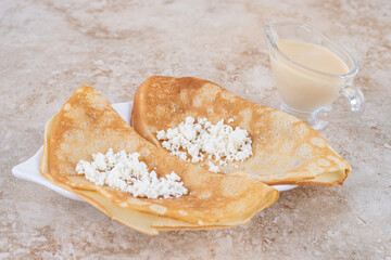 Roll pancakes with cottage cheese and a wooden spoon
