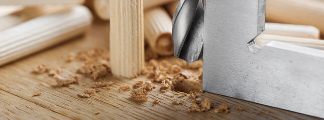 drill bit makes hole in wooden oak board for wooden dowel.