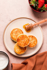 Cottage cheese pancakes, with white sauce and strawberries, on a beige table, top view, selective focus, no people,