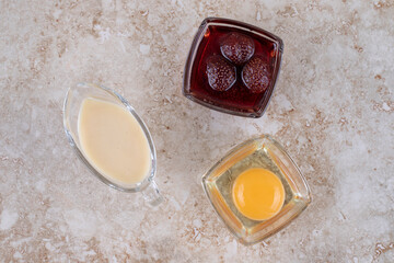 Raw egg yolk with strawberry jam on a marble background