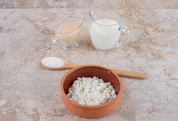 A clay bowl full of delicious cottage cheese and a wooden spoon of sugar