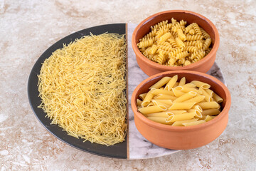 Various types of raw pasta on a marble background