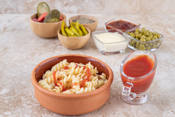 A clay bowl of tasty pasta with various vegetables
