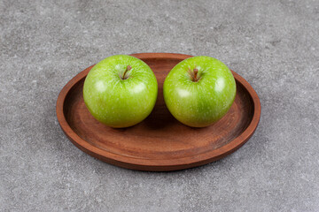 Two green fresh apples on wooden kitchen board