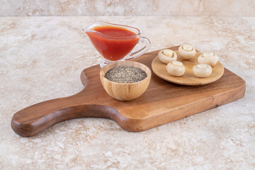 A wooden cutting board with mushrooms and ketchup