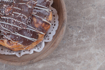 Chocolate coated cake in a wooden platter on marble background