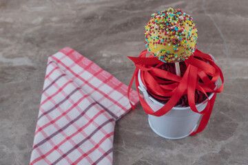 Bundle of ribbons and a lollipop in a bucketl on marble background