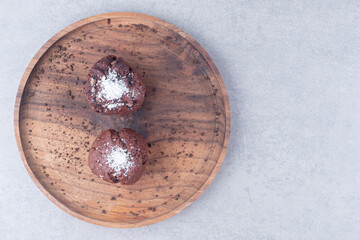 Chocolate cupcakes on a wooden tray on marble background