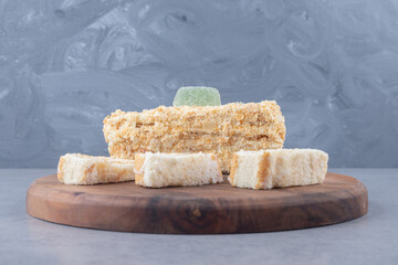 Delicious cake roll and slice on a wooden board on marble background
