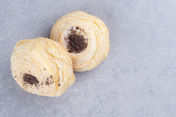 Two flaky cookies displayed on marble background
