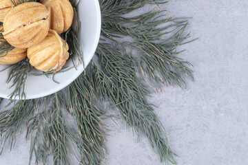 Handful of caramel filled cookies adorned with pine leaves on marble background