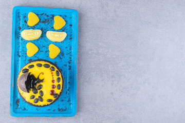 A small cake and marmelades on a blue platter on marble background
