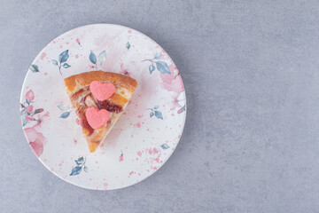 A slice of pie topped with marmelades on a platter on marble background