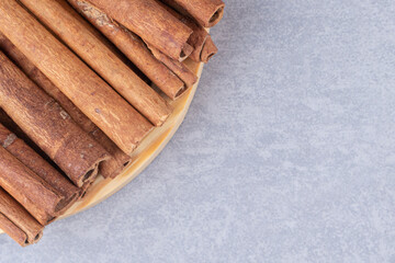 Bundle of cinnamon sticks on a small platter on marble background