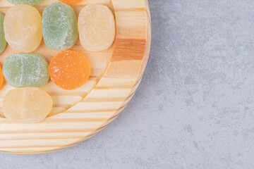 Marmelades neatly arranged on a wooden platter on marble background