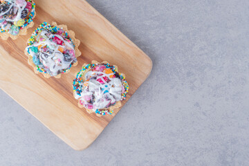 Cupcakes with candy topping on a wooden board on marble background