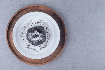 Chocolate cake on a platter on a wooden tray on marble background