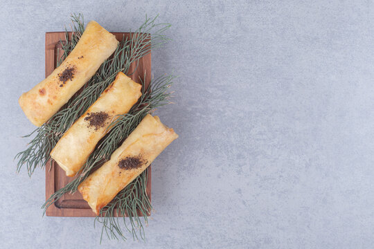 Serving of russian blins on a wooden platter, adorned with pine leaves on marble background