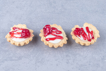 Strawberry syrup-topped cupcakes lined-up on marble background
