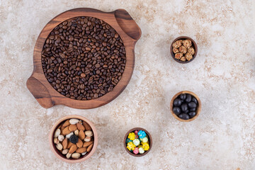 An arrangement of coffee beans, glazed peanuts, candies and assorted nuts on marble background