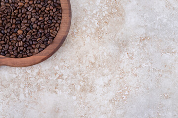 Coffee beans piled on a wooden tray on marble background