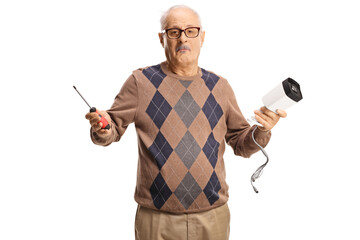 Confused mature man holding a security camera and a screwdriver