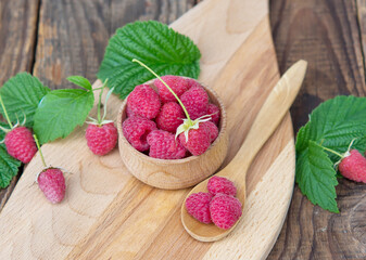 harvested red raspberries, large red garden raspberries in a wooden bowl on a wooden table