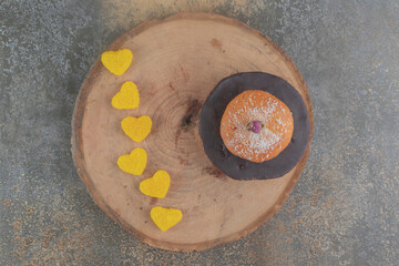 A small stack of cakes and marmelades on a wooden board on wooden background