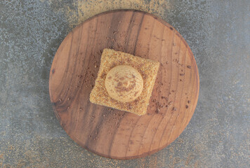 Cookie on a slice of cake on a board on wooden background