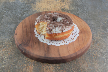 Bitten donut on a wooden board on wooden background