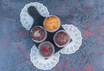 Cupcakes on a black platter on doilies on abstract background