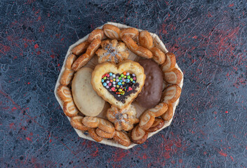Cookies and cakes bundled in a white basket on abstract background