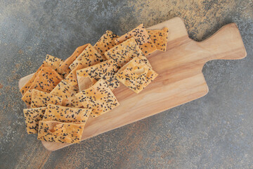 Tandoori bread slices with sesame seeds on board on wooden background