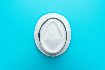 Top view of trilby over turquoise blue background. Flat lay top-down composition of white trilby hat. Minimalist flat lay photo of white hat in the center with copy space to the sides.