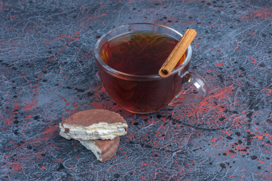 Broken Cookie, A Cinnamon Stick And A Cup Of Tea On Abstract Background