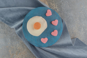 Heart shaped marmelades and chocolate topped cake on a board on wooden background