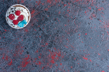 Cream topped cupcake in a patty case on abstract background