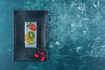 Cake slice with fruit topping on a platter on blue background